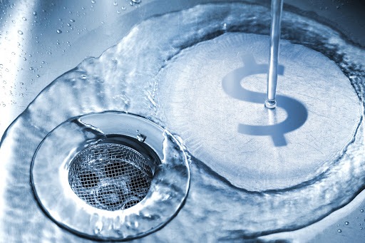 Water running down sink drain with dollar sign reflection.