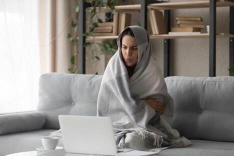 An image of someone who is cold at home due to a broken Furnace.