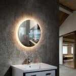 Modern bathroom with round LED mirror and sink.
