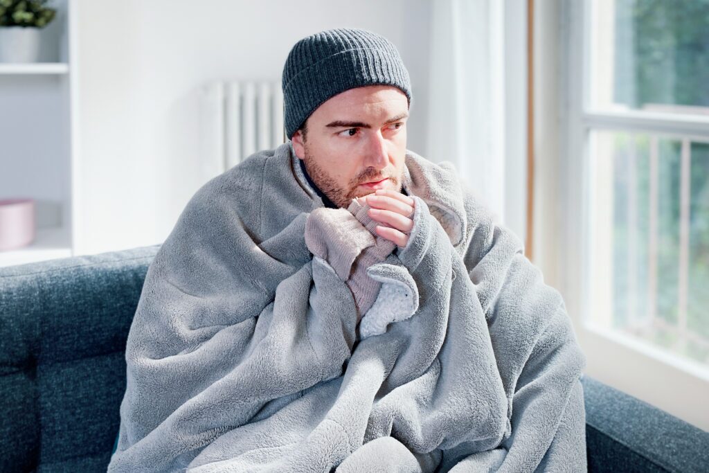 A person on a couch wrapped up in a blanket.